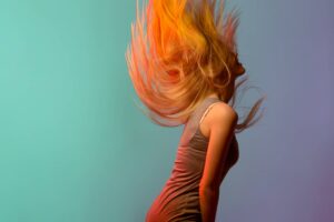 Giovane donna che getta indietro la testa con i lunghi capelli color arancione acceso.