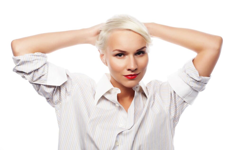 Giovane donna che indossa un’elegante camicia bianca. Il suo stile è alla moda e sofisticato. È riuscita ad ottenere i capelli bianchi, che porta tirati all’indietro. Ha un trucco leggero che sottolinea la sua bellezza naturale. La sua espressione è serena e sicura di sé.