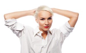 Giovane donna che indossa un’elegante camicia bianca. Il suo stile è alla moda e sofisticato. È riuscita ad ottenere i capelli bianchi, che porta tirati all’indietro. Ha un trucco leggero che sottolinea la sua bellezza naturale. La sua espressione è serena e sicura di sé.