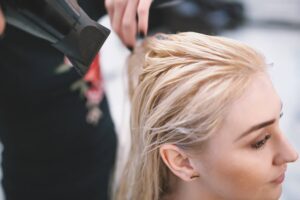 Una parrucchiera professionista asciuga i lunghi capelli di una cliente dopo aver utilizzato un metodo per schiarire i capelli.
