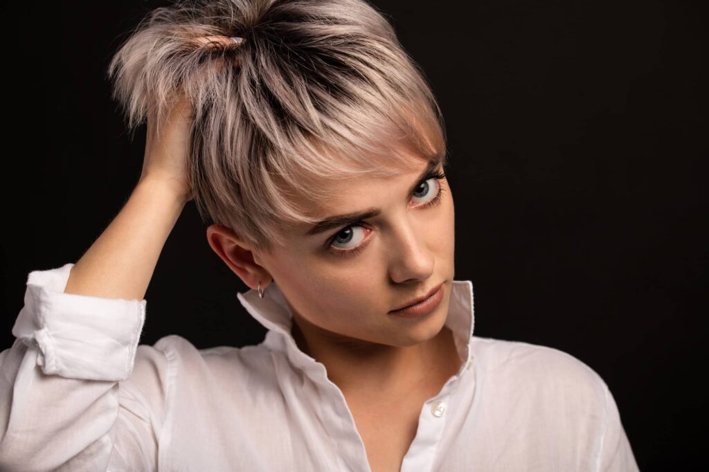 Ragazza con la testa inclinata e una mano tra i corti capelli fini, scuri alla radice e poi tinti d’argento. Ha scelto il miglior taglio per capelli fini per valorizzare la sua chioma.