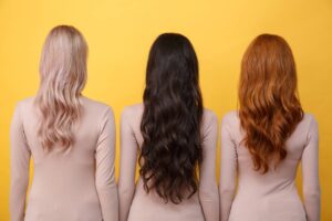Tre donne di spalle con i lunghi capelli mossi e scalati di diversi colori: una li ha biondi, una neri e una rossi. Ognuna di loro sa bene quando non scalare i capelli in base alle loro caratteristiche e preferenze personali.