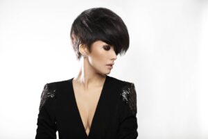 Donna alla moda con voluminosi capelli corti scuri che guarda di lato.