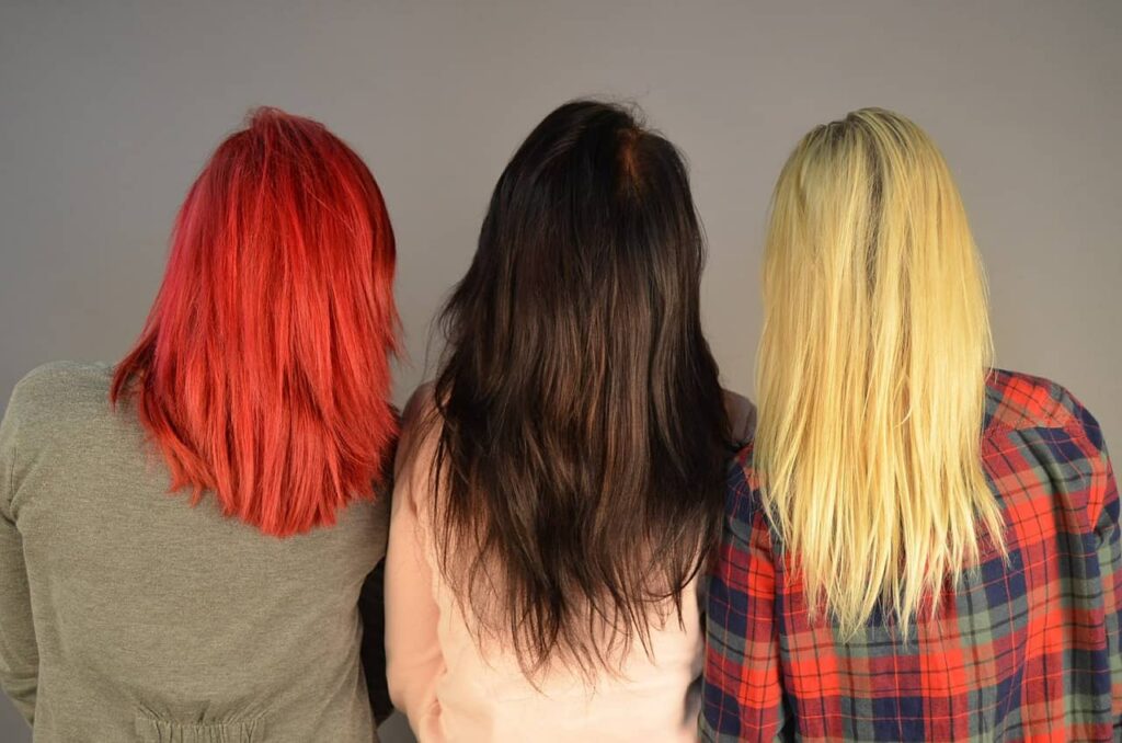 Foto di tre ragazze di spalle con i capelli lunghi di tre colori diversi. Da sinistra verso destra: rosso acceso, castano scuro, biondo oro.